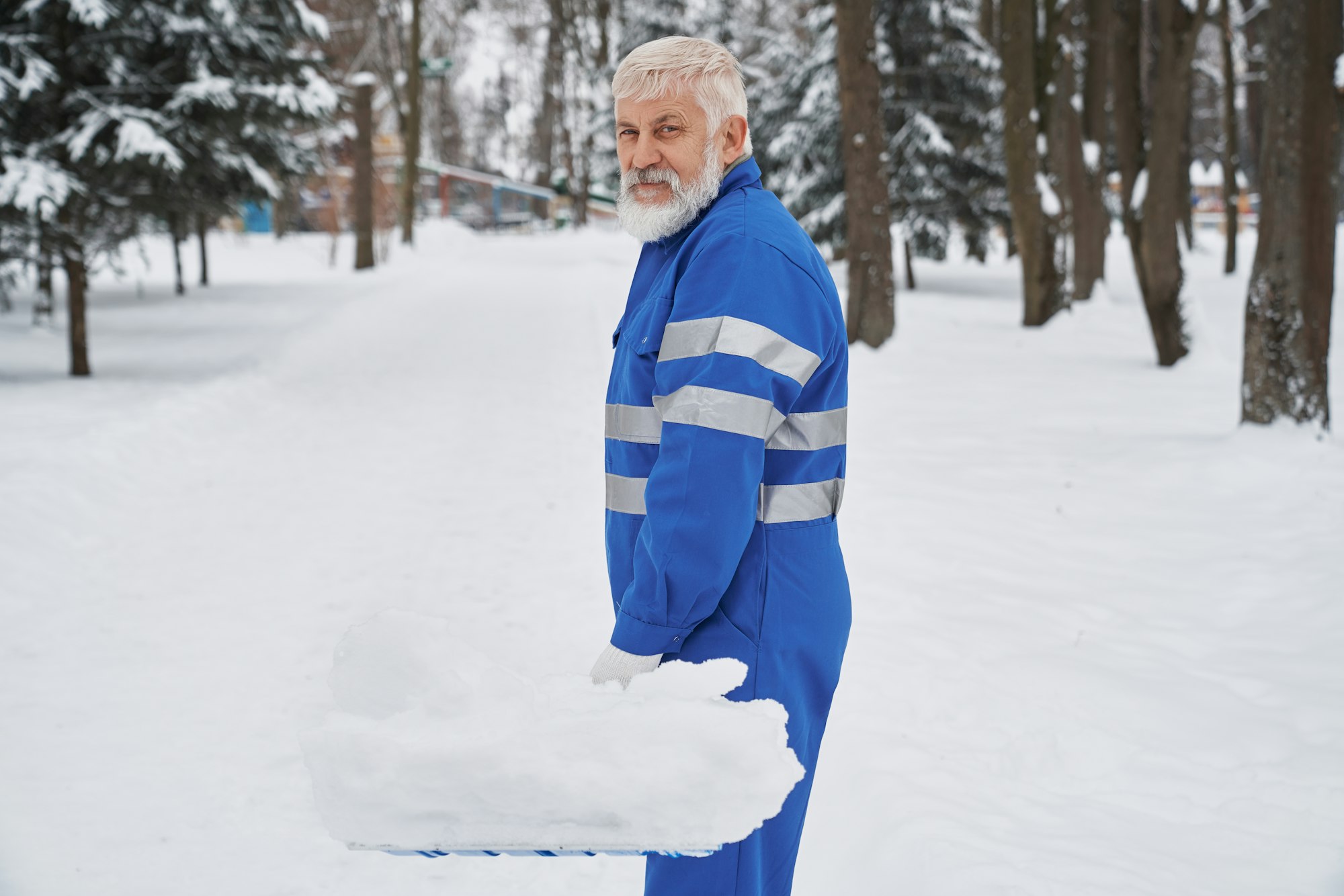 Portrait of cleaner in overalls with snow shover