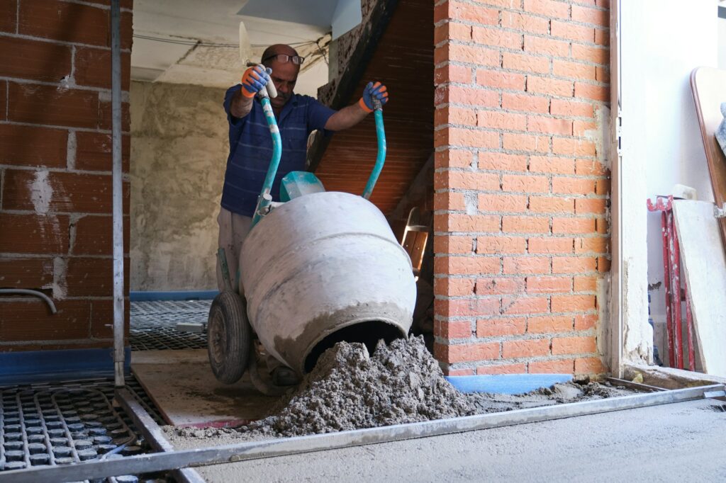 Builder pouring concrete from the concrete mixer to the radiant floor.