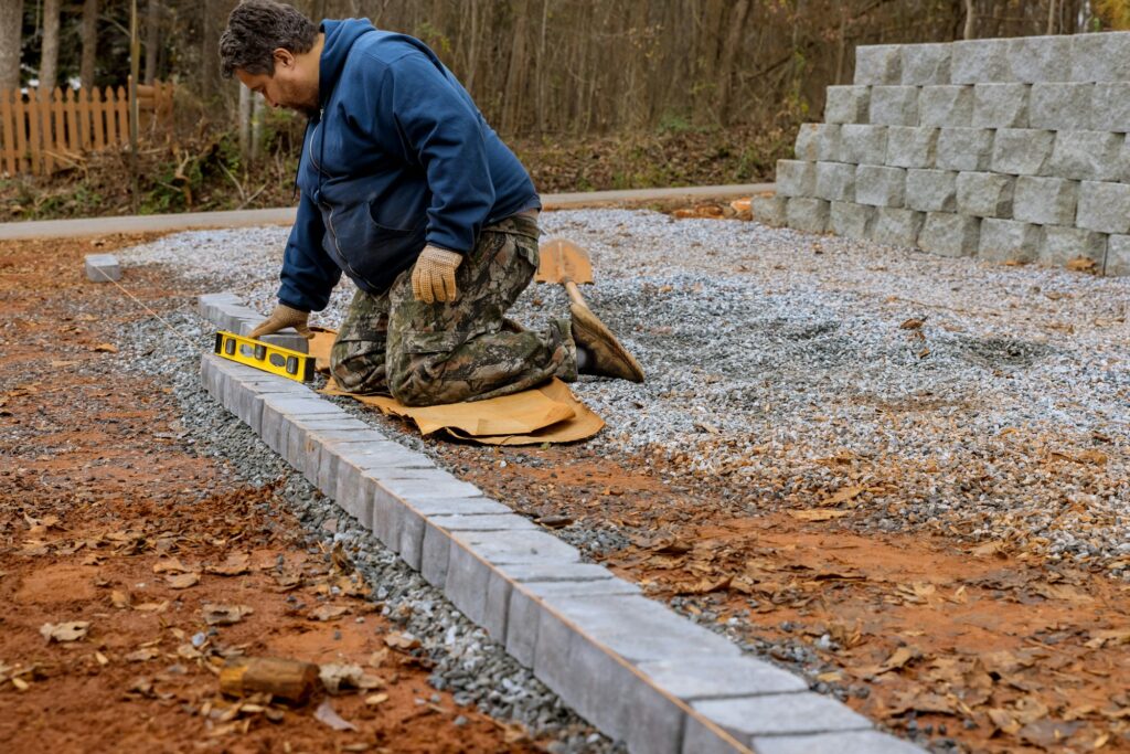 The construction worker is installing and arranging the precast concrete pavers stones for the road
